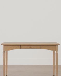 a wooden table sitting on top of a hard wood floor next to a white wall