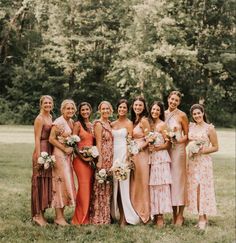 a group of women standing next to each other in front of some trees and grass