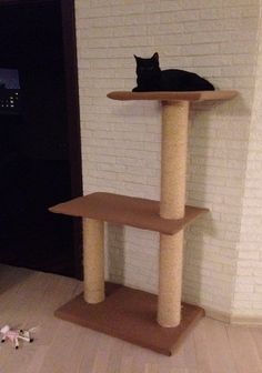 a black cat sitting on top of a wooden scratching tower