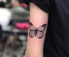 a black and white butterfly tattoo on the arm