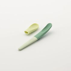 two toothbrushes sitting next to each other on a white surface, one green and the other yellow