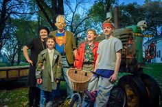 a group of people standing next to each other in front of a tractor with a face painted on it