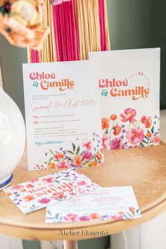 the table is set up with two cards and some flowers in vases on it