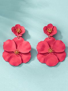 two pink flower shaped earrings on a blue background