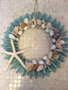 a wreath made out of sticks and seashells on a tile floor with a starfish