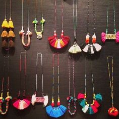 there are many different necklaces hanging on the wall with tassels attached to them