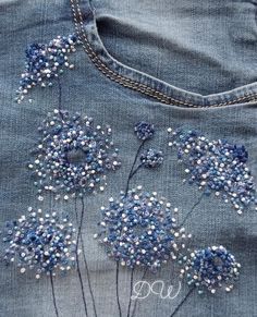 some blue flowers are embroidered on the back of someone's jean jacket with beads