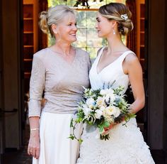 two women standing next to each other in front of a door with flowers on it