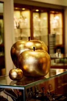 two golden apples sitting on top of a glass table