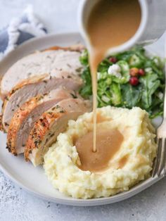 a plate with mashed potatoes, meat and gravy being poured onto it