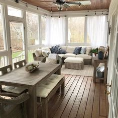 an outdoor living room with white couches and blue pillows on the back porch area