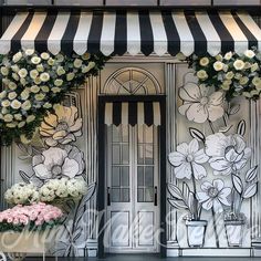 flowers are displayed in front of a storefront with striped awnings on the windows