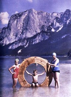 three children are standing in the water with their arms around a life preserver on a beach