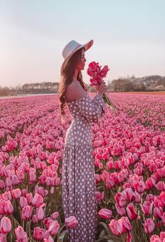 a woman in a polka dot dress standing in a field of pink tulips