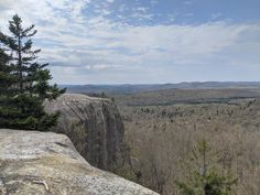 a rocky outcropping with trees and mountains in the distance