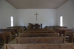 an empty church with wooden pews and a cross on the wall