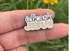 a hand holding a small white and yellow sticker that says i'd ask jesus