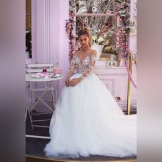 a woman in a wedding dress is standing near a table with pink flowers on it