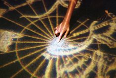 a person's hand on the ground in front of a circular object with light coming from it