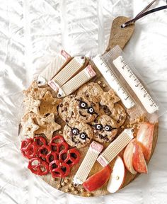 an apple, cookie and measuring tape arranged on a wooden platter with red apples