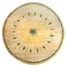 a round rug with an intricate design on the center and bottom, in yellow tones