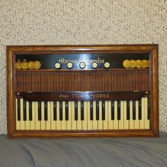 an old piano sitting on top of a bed in a room with carpeted walls