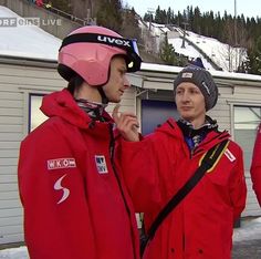 three men in red jackets standing next to each other on a snow covered ground with skis