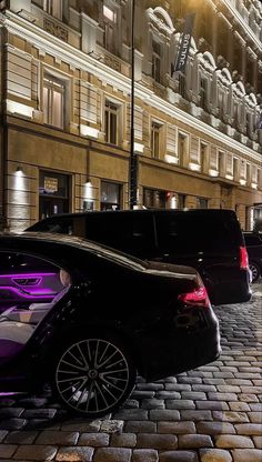 two cars parked in front of a building at night