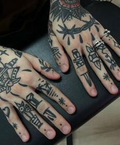 a person with tattoos on their hands and two fingers, sitting in front of a black chair