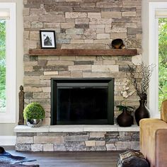 a living room with a stone fireplace and two vases on top of the mantle