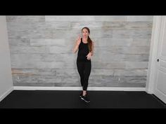 a woman standing in front of a wall with her hands on her hips and looking at the camera