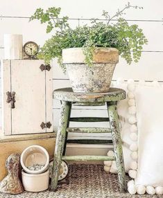 a potted plant sitting on top of a wooden stool next to a white cabinet