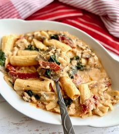 a pasta dish with spinach and tomatoes in a creamy sauce on a white plate