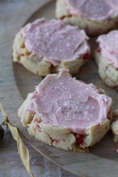 several cookies with pink icing sitting on a plate