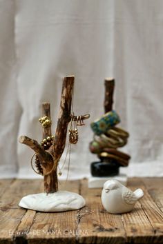 a wooden table topped with two small white birds next to a tree branch and ring holder