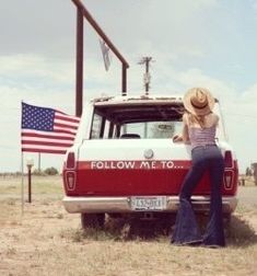 a woman leaning on the back of a truck with an american flag in the background