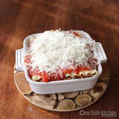 a casserole dish with cheese and sauce on a wooden table top, ready to be eaten