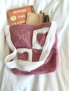 there is a crocheted purse on the bed with books and other items in it