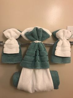 three towels hanging on a towel rack in a bathroom with two white and one green ones