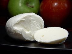 there are two pieces of cheese on the plate next to an apple and another piece of cheese