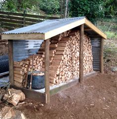 a pile of wood sitting in front of a shed on top of a dirt field