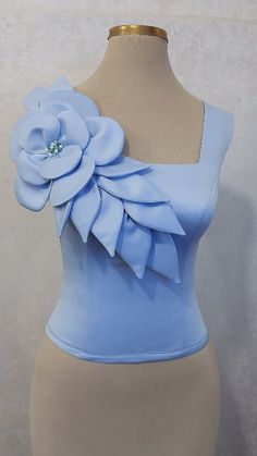 a mannequin wearing a blue top with a large flower on the front and side