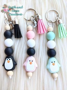 four different key chains with penguins and tassels hanging from them on a fur surface