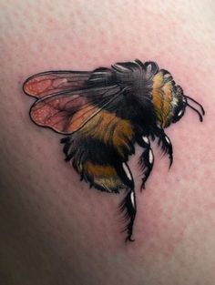 a tattoo of a bee on the back of a woman's thigh, with black and yellow stripes