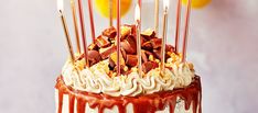 a birthday cake with chocolate, marshmallows and candles on top that are drizzled with caramel