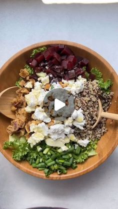 a wooden bowl filled with vegetables and other food on top of a white countertop