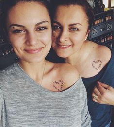 two women with tattoos on their chest posing for the camera