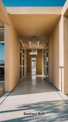 an empty hallway between two buildings with glass doors on both sides and a ceiling fan hanging from the ceiling