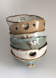 four ceramic bowls stacked on top of each other with hearts in the center and holes in the middle