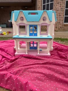 a pink and blue doll house sitting on top of a bed in front of a brick building